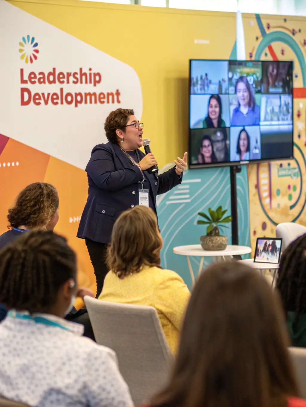 A group of professionals engaged in a leadership training session with a coach facilitating discussion, representing Leadership Development Workshops.